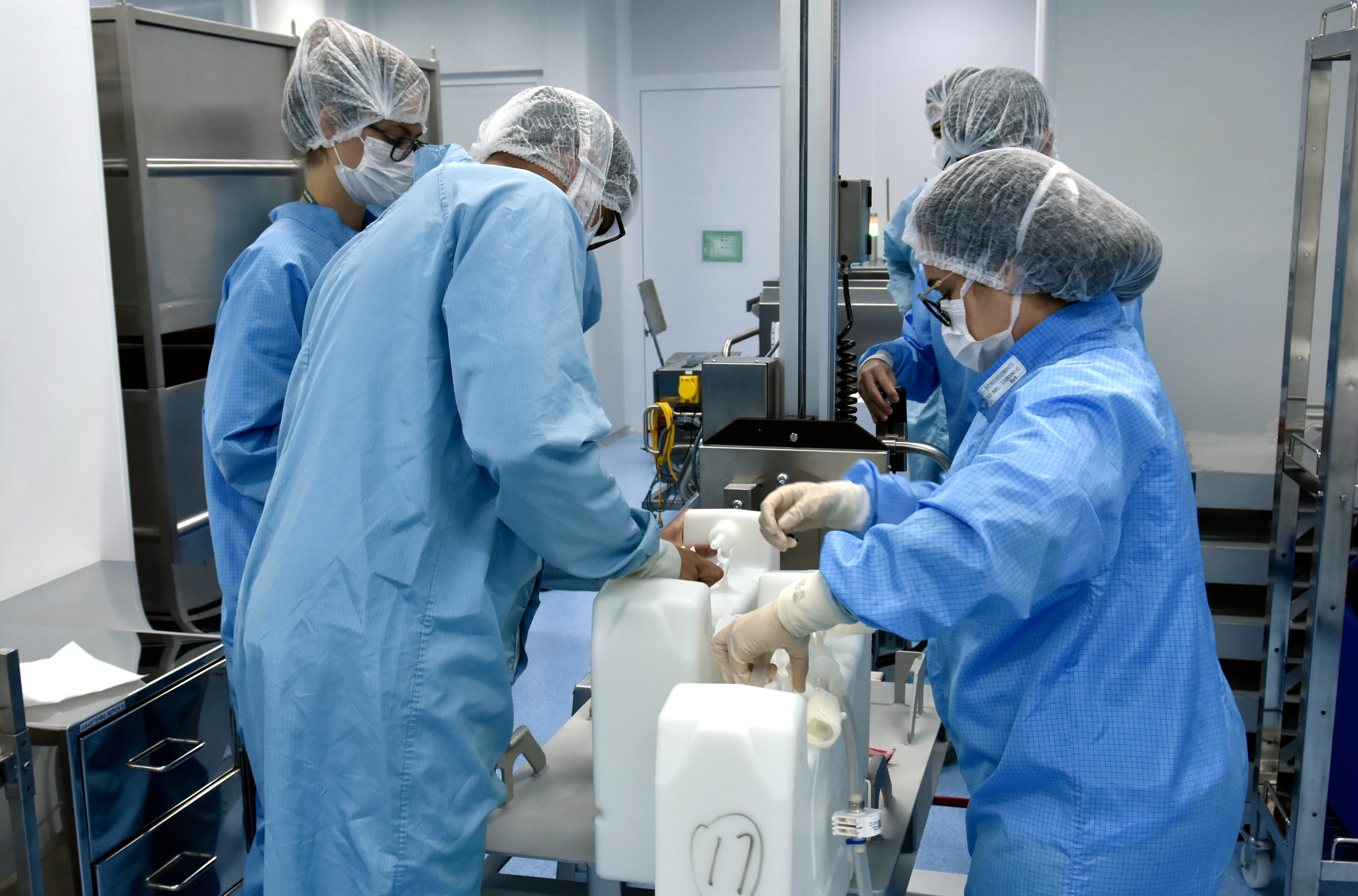 Trabalhadores manipulando o CryoVault, recipiente onde o IFA fica armazenado. Centro Henrique Penna, em Bio-Manguinhos/Fiocruz. Rio de Janeiro (RJ), 2021. Foto: Rodrigo Mexas.