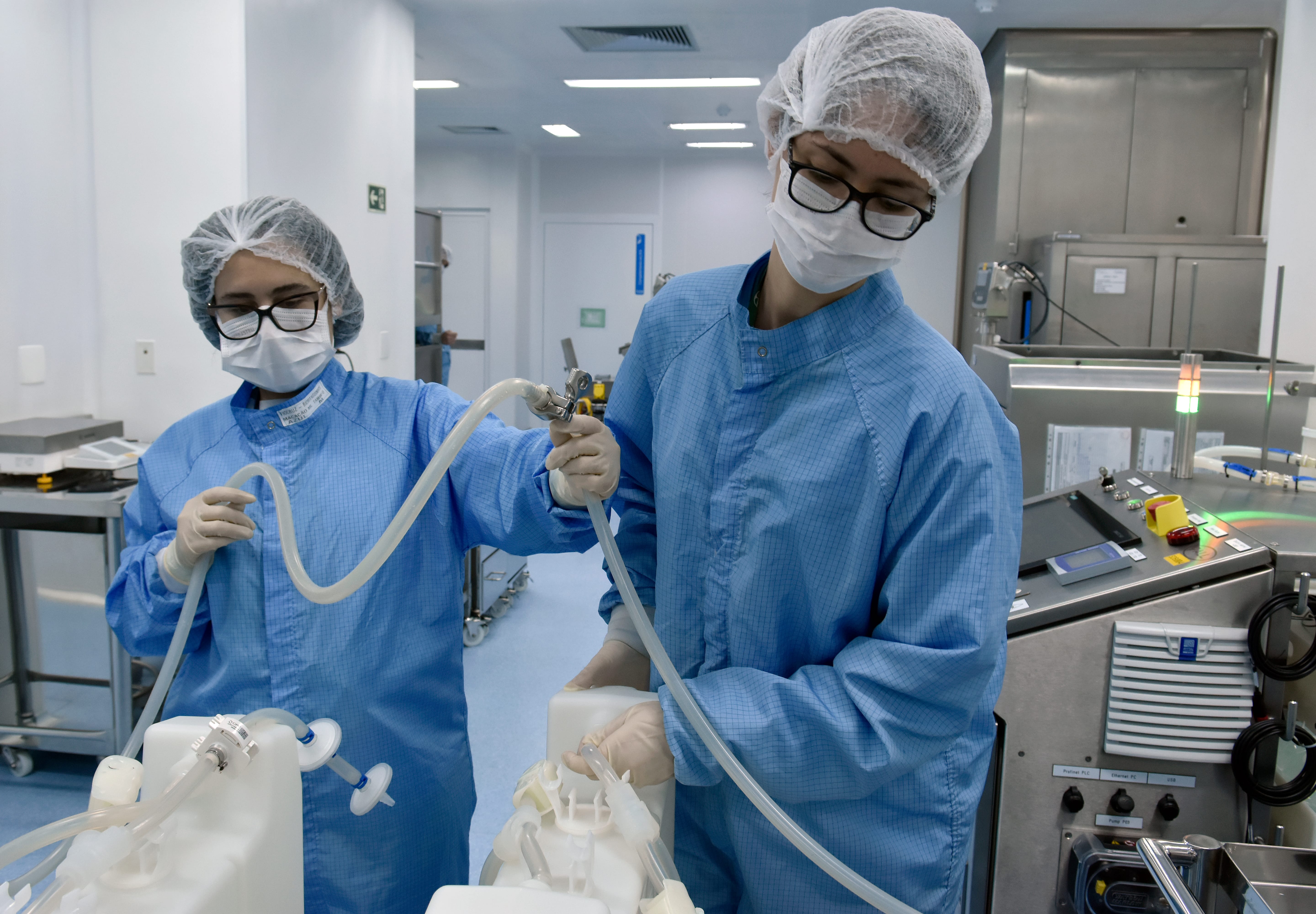 Trabalhadores manipulando o CryoVault, recipiente onde o IFA fica armazenado. Centro Henrique Penna, em Bio-Manguinhos/Fiocruz. Rio de Janeiro (RJ), 2021. Foto: Rodrigo Mexas.